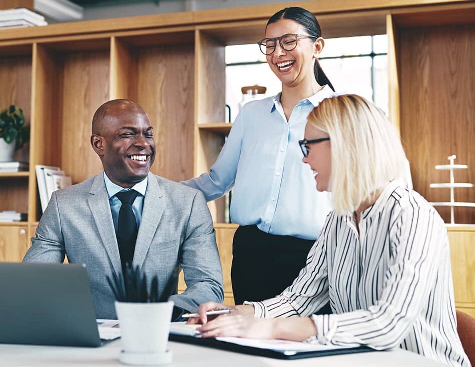 Diverse group of businesspeople laughing together around an office