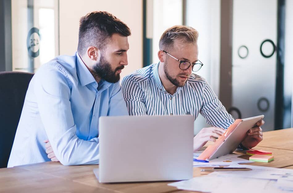 male colleagues concentrated on reading report talking to each other for analyzing data